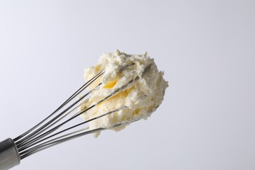 Fototapeta premium Whisk with whipped cream on white background, closeup. Space for text