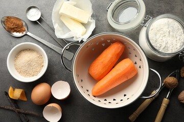 Different ingredients for making carrot cake and kitchenware on dark textured table, flat lay