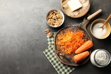 Different ingredients for making carrot cake and kitchenware on dark textured table, flat lay. Space for text