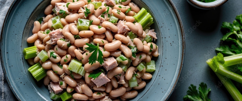 Aufkleber butter bean tuna and celery salad in a blue bowl garnished with parsley on a gray table with fresh c