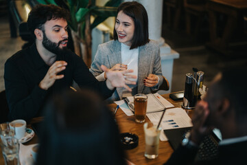 A lively group of colleagues discussing ideas in a casual cafe setting, fostering collaboration and positive interaction in a relaxed professional atmosphere.