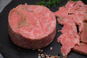 Vegan ham made of wheat gluten, shaped and cooked in a ham press. Sliced, slate board.