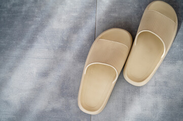 one pair of beige rubber slippers stand on the gray granite floor