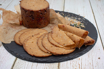 Seitan shaped and cooked in ham press, sliced on slate board. Vegan protein, plant based alternative to meat.
