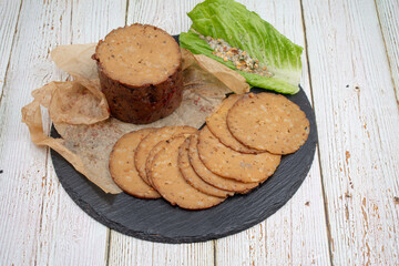 Seitan shaped and cooked in ham press, sliced on slate board. Vegan protein, plant based alternative to meat.