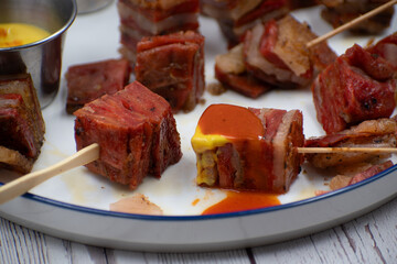 Vegan seitan pork belly appetizer, white plate, wooden table