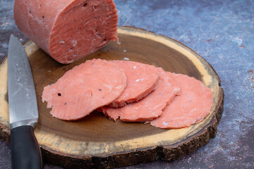 Vegan ham made of wheat gluten, shaped and cooked in a ham press. Sliced, wooden board.