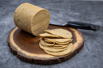 Vegan ham made in ham mold, sliced, wooden board. Mock vegan meat as plant based alternative to meat.
