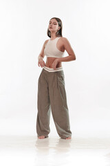 Fototapeta premium Young girl in trousers posing on a white background