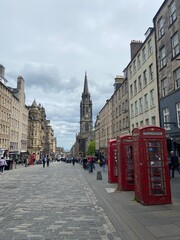 Iconic red telephone booths along the Royal Mile in Edinburgh, Scotland, with St. Giles' Cathedral in the background. A classic urban scene of the historic Old Town