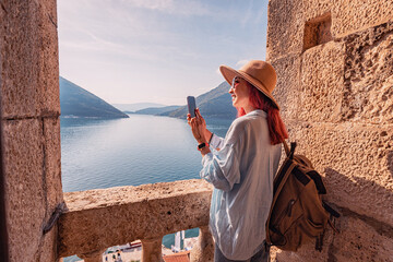 Tourist taking pictures of bay of kotor from old fortress walls