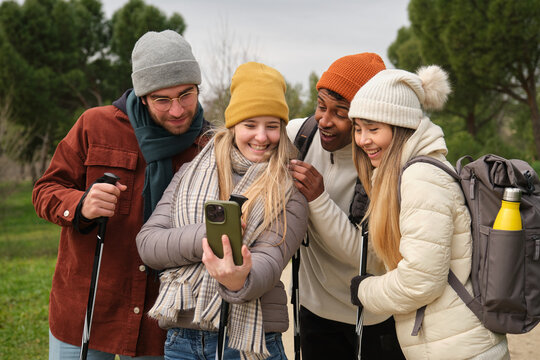 Group of hikers taking a selfie with a smartphone, using nordic walking poles on a beautiful day