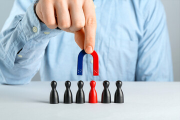 Man with magnet attracting game pieces at white table, closeup