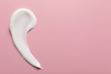 Cream on pink background, top view and space for text. Sample of cosmetic product