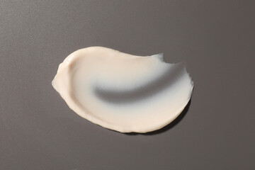Cream on grey background, top view. Sample of cosmetic product