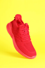 Stylish red sneaker in air against yellow background