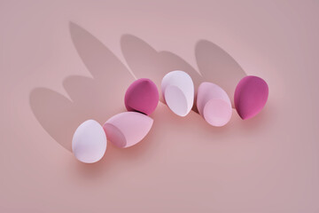 A set of makeup sponges on a pink background.