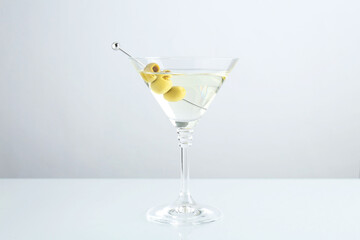 Martini cocktail with olives in glass on light table