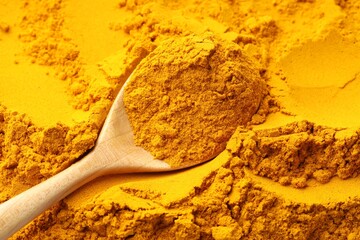 Turmeric powder in spoon on spice, closeup