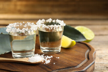 Tequila shots with salt on wooden table, closeup