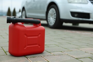 Red plastic canister with spout on pavement outdoors