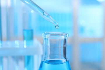 Dripping liquid into flask on light background, closeup