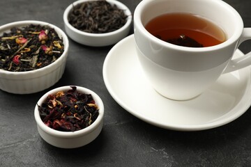 Aromatic tea and dried leaves on black table, closeup