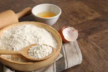 Rolling pin, flour and yolk on wooden table, closeup. Space for text