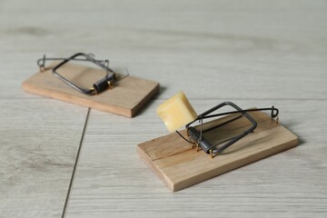 Spring-loaded bar mousetraps with piece of cheese on floor, closeup