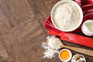 Rolling pin and ingredients for dough on wooden table, flat lay. Space for text