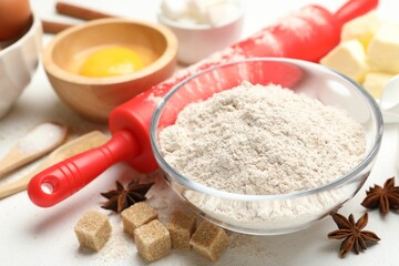 Rolling pin and different ingredients on white table, closeup