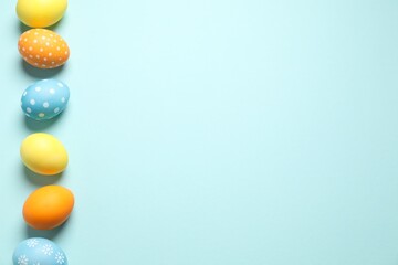 Beautiful decorated Easter eggs on light blue background, flat lay. Space for text