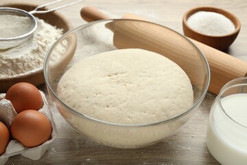 Rolling pin and different ingredients on light wooden table, closeup