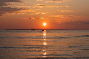 Sunset over the Baltic Sea in Estonia. Orange sky, silhouettes of boats and reflections on the water create a peaceful atmosphere.