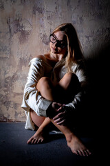 A serene woman poses by a textured wall, radiating calmness, elegance, and introspection
