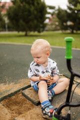 Little boy plays in sand at park during sunny day, enjoying outdoor fun and creativity