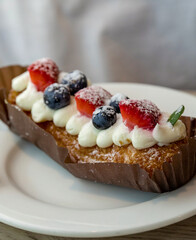 Dessert with strawberries, blueberries, and whipped cream is on a white plate