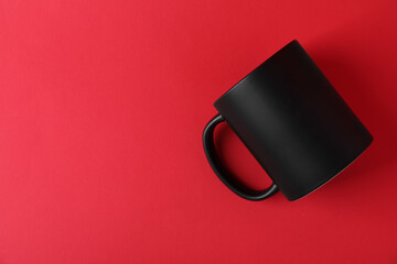 One blank black mug on red background. Mockup for design