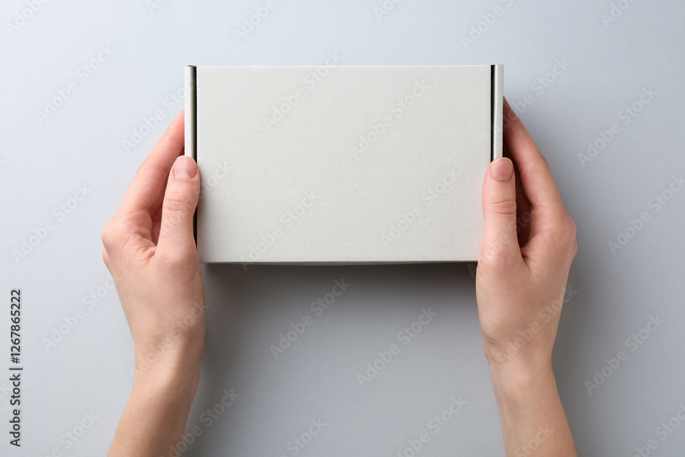 Wall mural Woman with blank cardboard box on white background, top view. Mockup for design