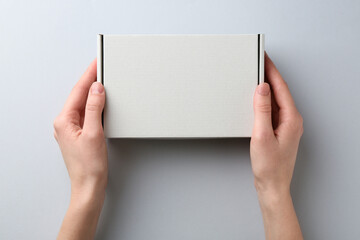 Woman with blank cardboard box on white background, top view. Mockup for design