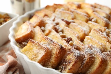 Delicious bread pudding with raisins and powdered sugar in dish, closeup