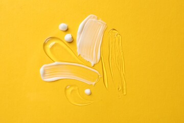 Samples of different cosmetic products on yellow background, flat lay