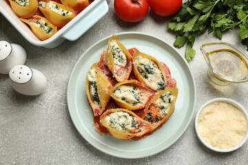 Delicious shell pasta stuffed with ricotta and spinach served on light grey table, flat lay