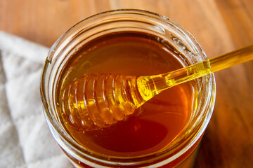 Glass bowl of natural honey and yellow spoon.