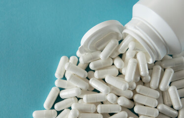 White transparent tablets or pills in white bottle with blue background.