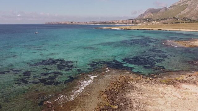 Aerial drone view of Macari (Makari), Sicily. Crystal clear turquoise waters, rugged cliffs, golden sandy beaches. A serene natural landscape with Mediterranean charm near San Vito lo Capo.	