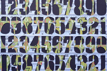 layered stencils with machine-cut numbers in blue and green with measuring tape motif
