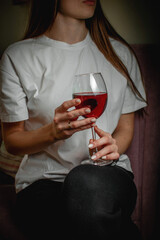Elegant Young Woman Holding a Glass of Red Wine in a Relaxed Setting