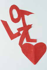 abstractly the word "love" hand cut from silky fibrous paper and a red paper heart