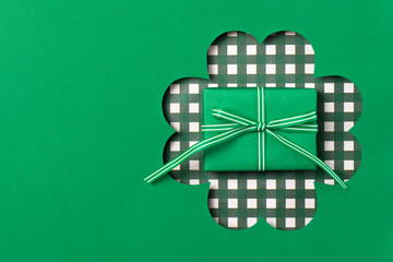 Green gift box inside a shamrock cutout. Festive St. Patrick’s Day background. Minimal holiday...